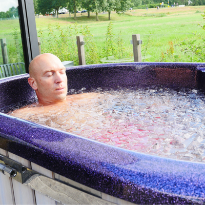 Man ligt tot aan zijn schouders in het ijskoude water van de Next Level Icetub