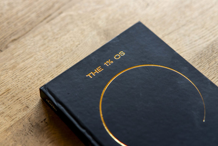 Kaft van The 1% OS Notebook op een houten tafel
